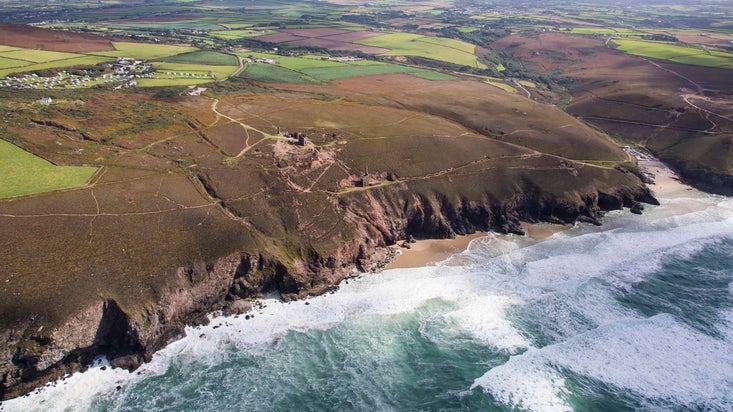 An aerial view of the Wheal Coates coastline and Chapel Porth beach on a bright day